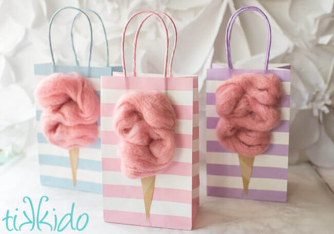 Cotton candy favor bags made with pastel striped plain gift bags and extra chunky pink roving yarn.