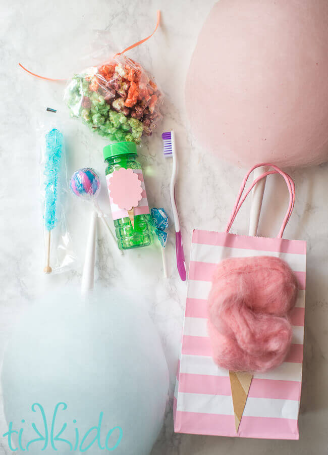 Cotton candy favor bags filled with cotton candy lollipops, rock candy, cotton candy popcorn, and a toothbrush.