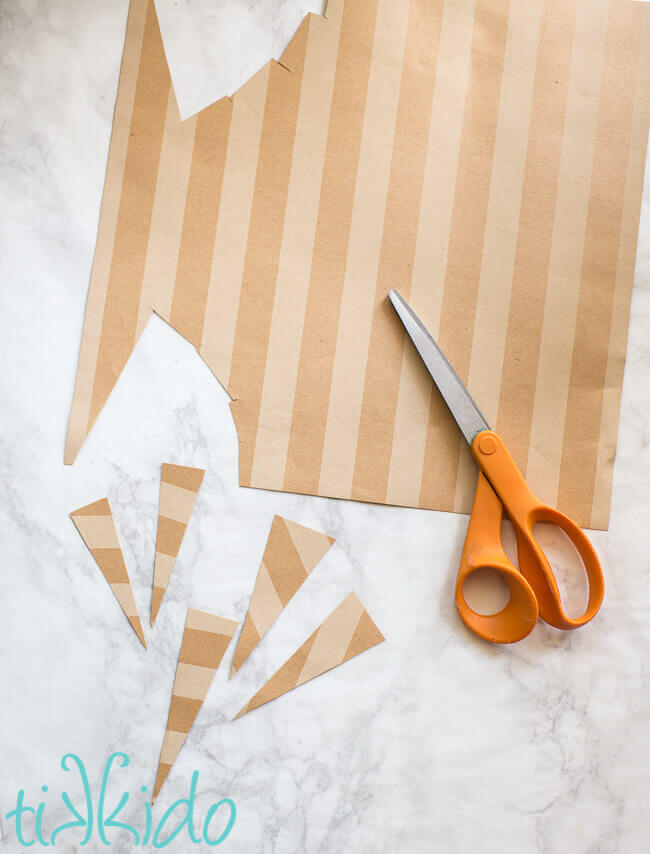 Brown striped scrapbook paper being cut into triangles for the cotton candy favor bags.