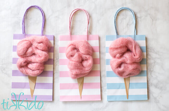 Cotton candy favor bags made with pastel striped plain gift bags and extra chunky pink roving yarn.