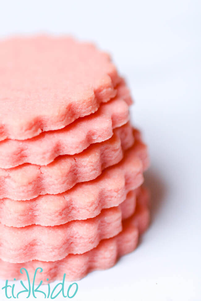 Stack of pink, round cotton candy sugar cookies on a white background.
