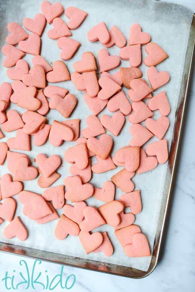 Tiny heart shaped pink sugar cookies baked and ready to decorate as Conversation Heart Cookies