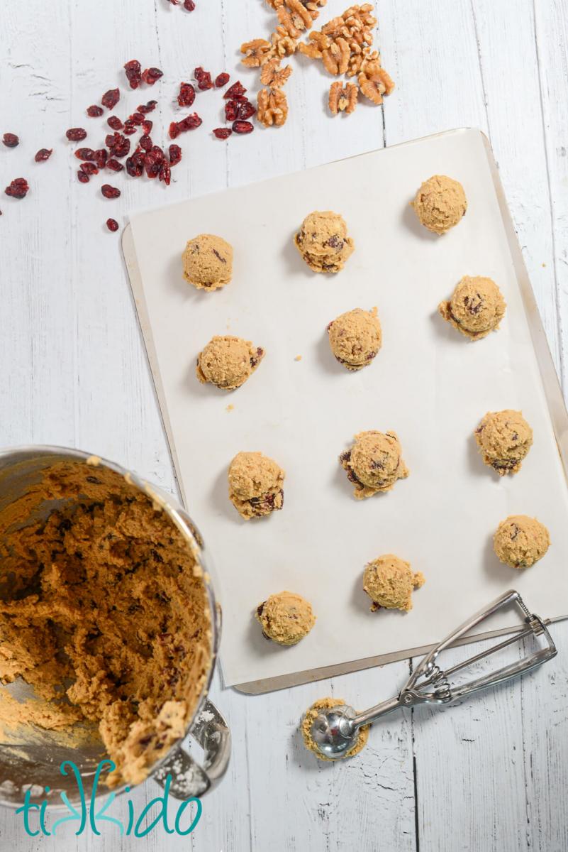 Cranberry Walnut Cookie dough scooped out and ready to bake on a parchment lined baking sheet.