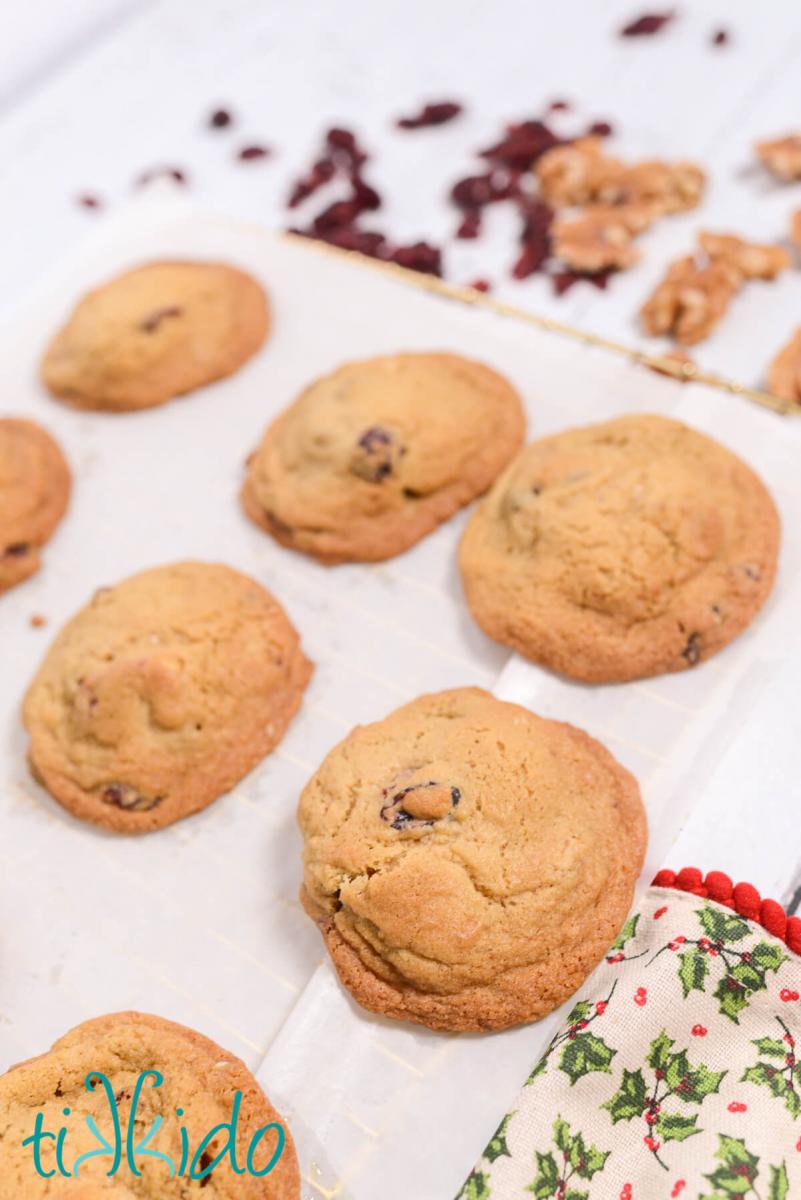 Freshly baked Cranberry Walnut Cookies cooling on parchment paper on a wire cooling rack.