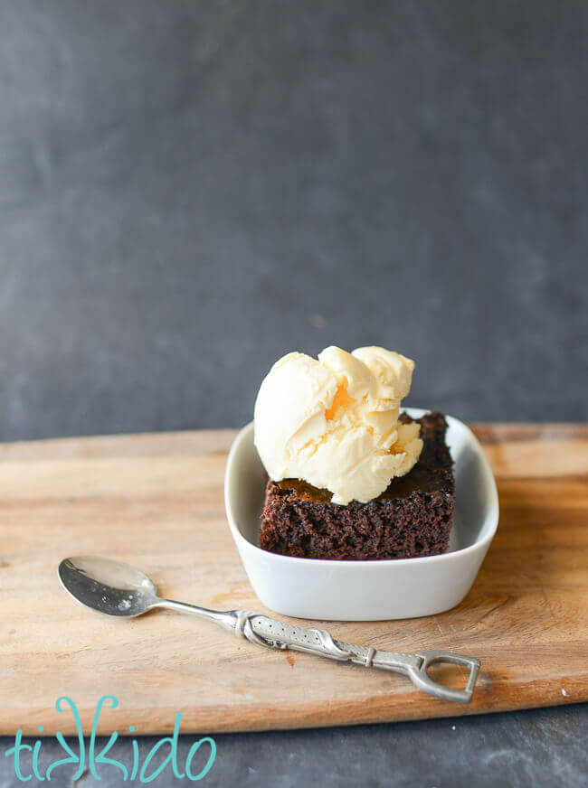 Slice of Crazy Cake chocolate cake in a white bowl, topped with vanilla ice cream.