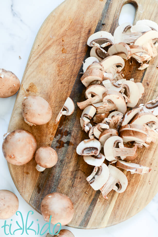 Fresh mushrooms sliced on a cutting board for a Cream of Mushroom Soup Recipe.