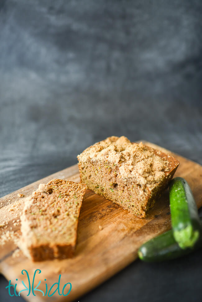 Zucchini bread with streusel topping on a wooden cutting board.