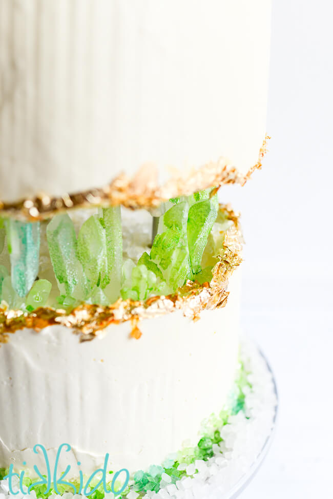 Closeup of the center of the cake, the space between the top and bottom tier, where green isomalt crystals appear to be "growing."  Real gold leaf edges the top edge of the bottom cake, and the bottom edge of the top cake.