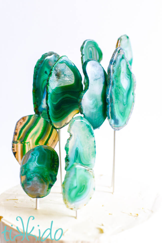 Closeup of the Crystal Themed Birthday Party cake topper made from nine green slices of agate stone, arranged at different heights on white lollipop sticks.
