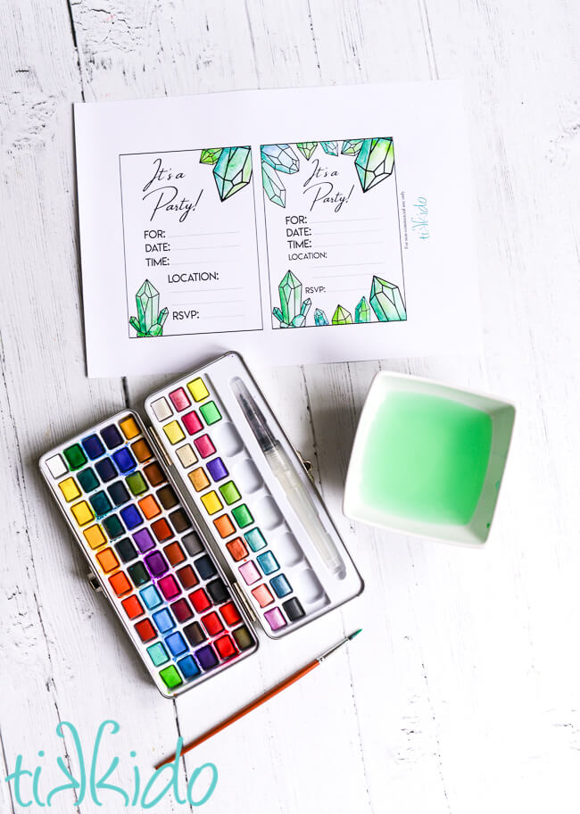Printable crystal birthday invitations being painted with a set of watercolor paints.
