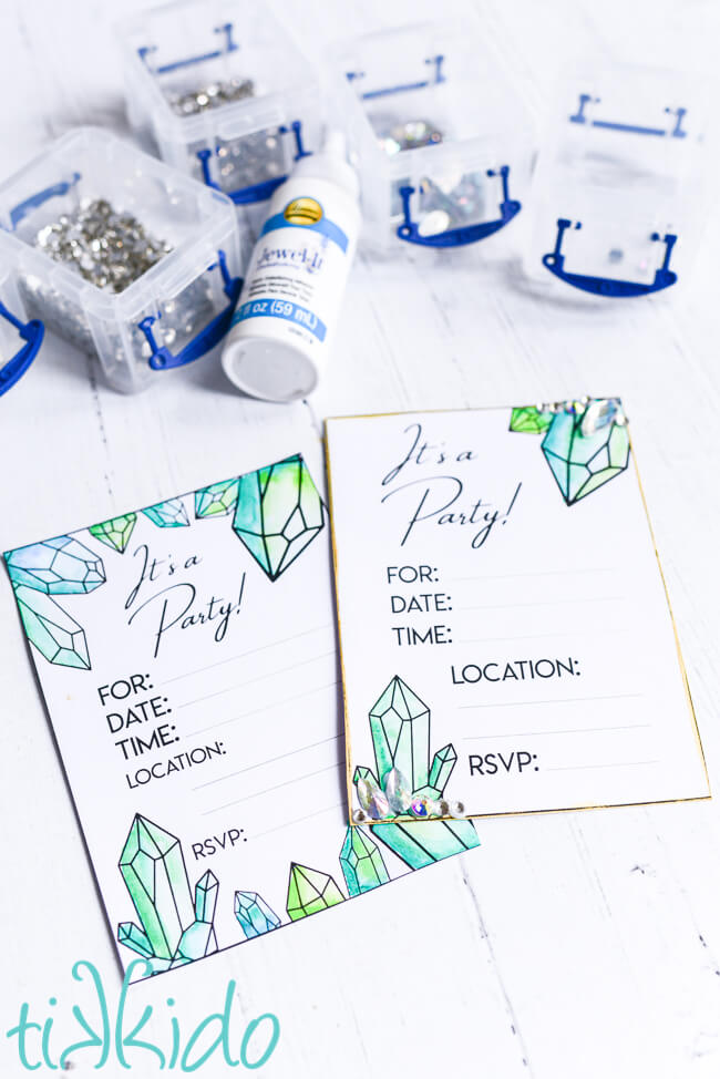 Two printable crystal birthday invitations, painted with green watercolor paints, being embellished with Czech Preciosa rhinestones using Aleene's Jewel-it glue.