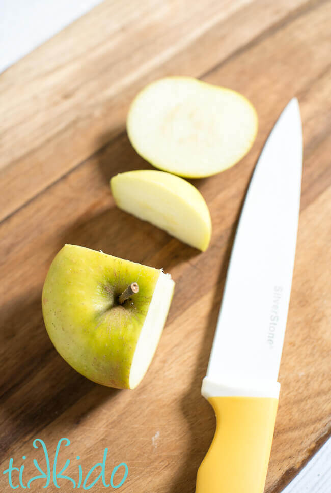 Apple sliced on a wooden cutting board using pastry chef apple slicing methods.