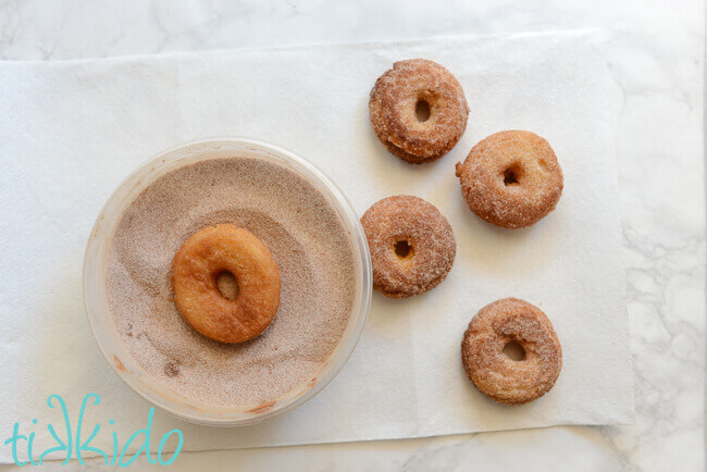 Hot cake Doughnuts being coated in cinnamon sugar