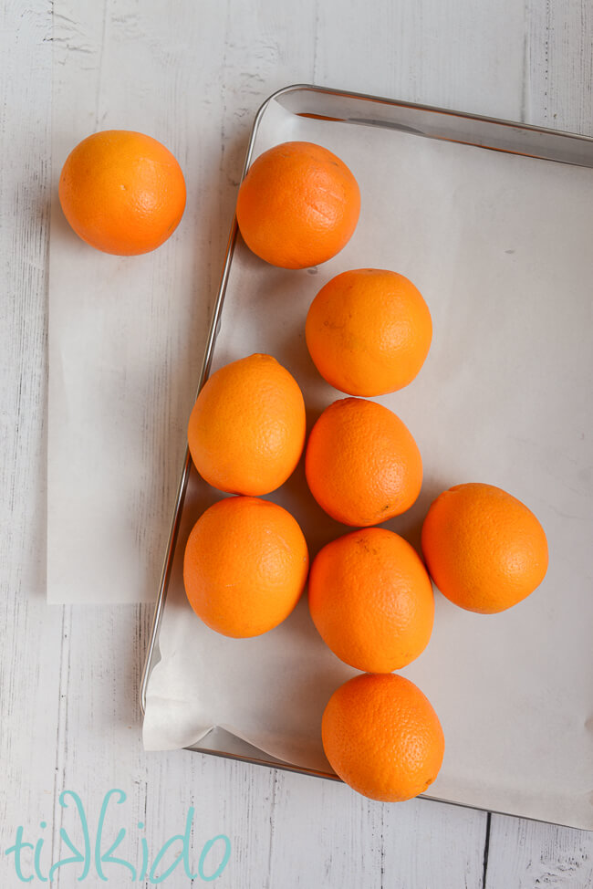 Fresh oranges on a parchment-lined baking sheet for making Dried Orange Garland.