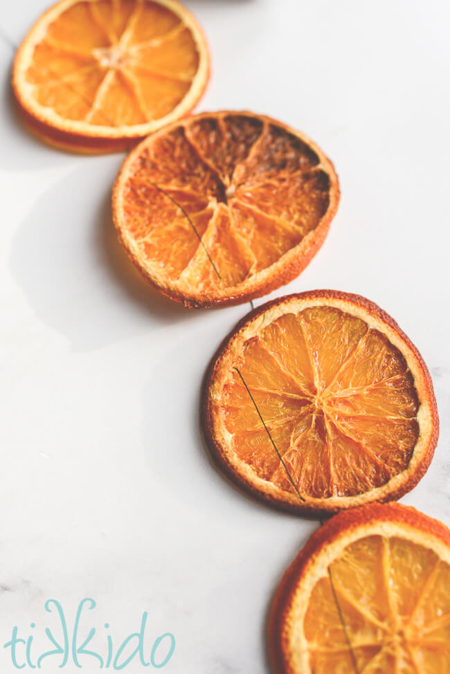 Closeup photo of slices of dried orange garland strung with a black thread.