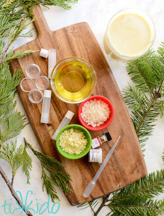 Ingredients and supplies for making Eggnog Lip Balm on a wooden cutting board.