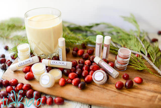 Eggnog and cranberry homemade lip balm on a wooden cutting board.