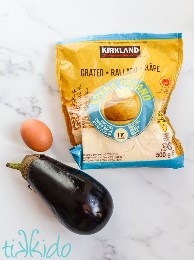 Ingredients for Keto Eggplant Parmesan made in a waffle iron, including a fresh eggplant, an egg, and grated parmesan cheese..