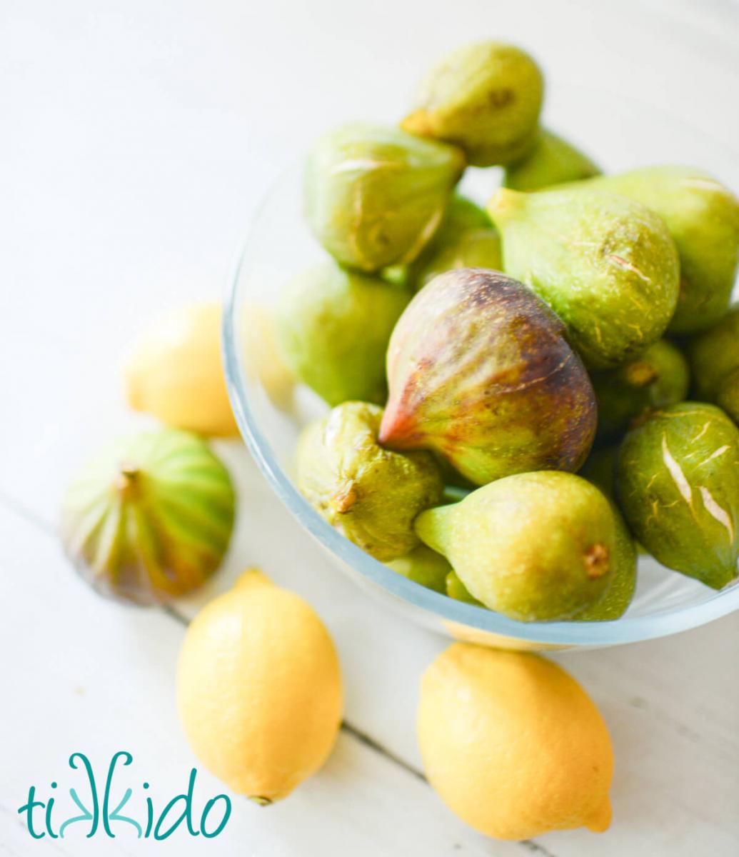Bowl of fresh figs and lemons on a white wooden table.