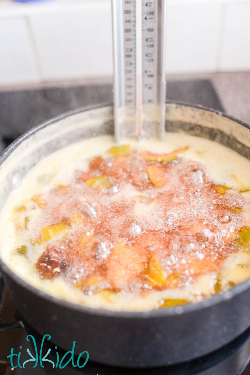 Fig jam cooking on the stovetop with a candy thermometer in the pot to measure the temperature.
