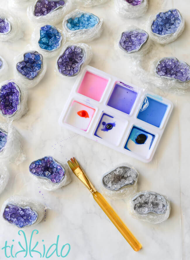 Clear sugar crystal and gum paste geode cupcake toppers being painted with pink, purple, and blue food coloring.