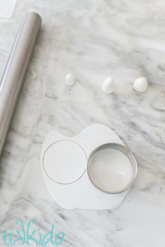 Gum paste or fondant being rolled out and cut into circles with a cookie cutter to make edible ghost cupcake toppers.