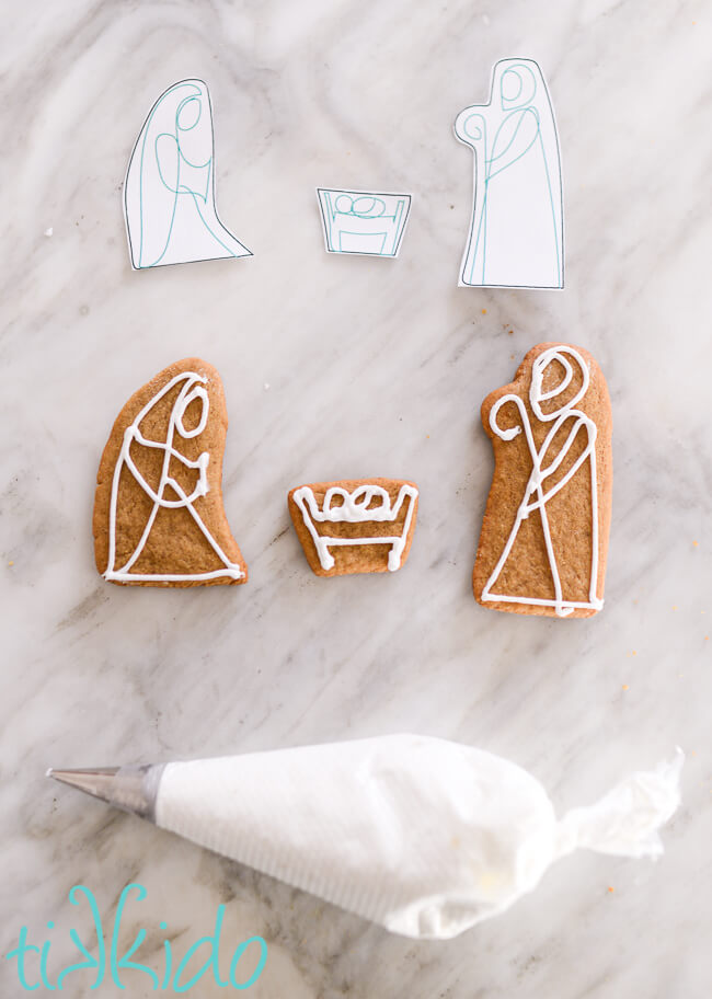 Baked gingerbread nativity figures decorated in a simple, line-drawing style with royal icing.