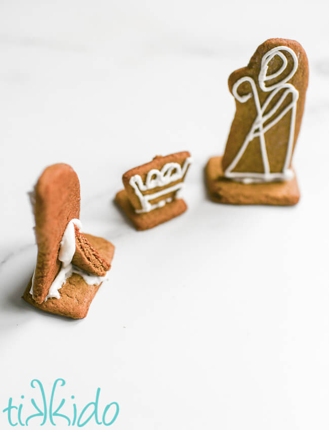Gingerbread nativity figures standing vertical on cookie bases, with the Mary figure turned backward so viewers can see the triangular support on the back.