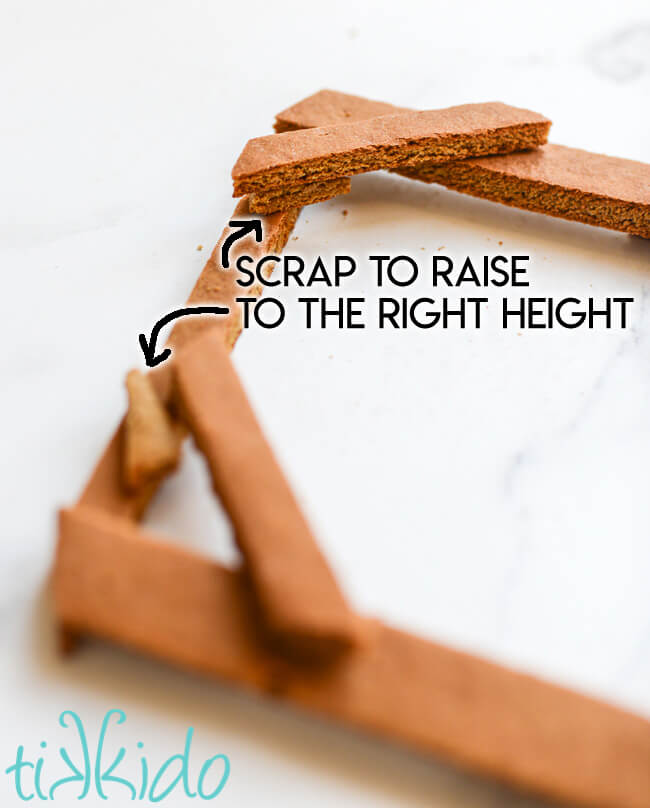 Pieces of the front beam section of the gingerbread nativity being assembled, with text showing where to use scraps to level the gingerbread.