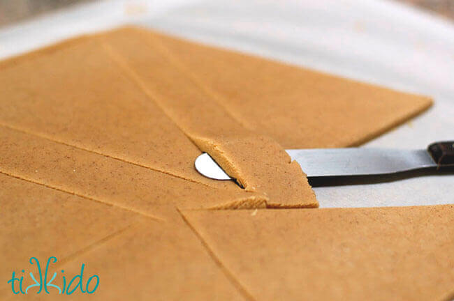 Gingerbread house dough being cut into shapes for making gingerbread houses.