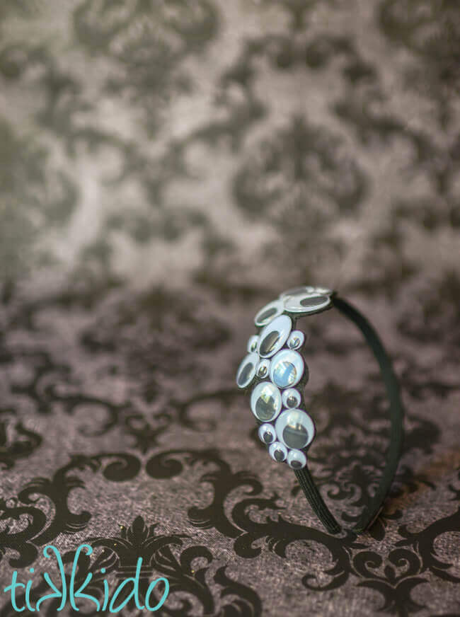 Googly eyes Halloween headband on a grey damask background.