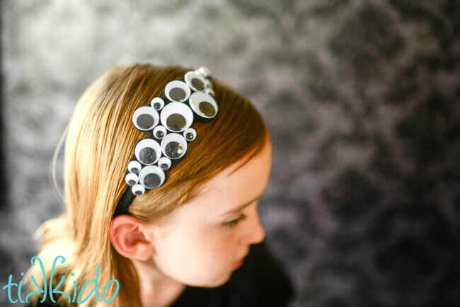 Little girl wearing a Googly eyes Halloween headband.