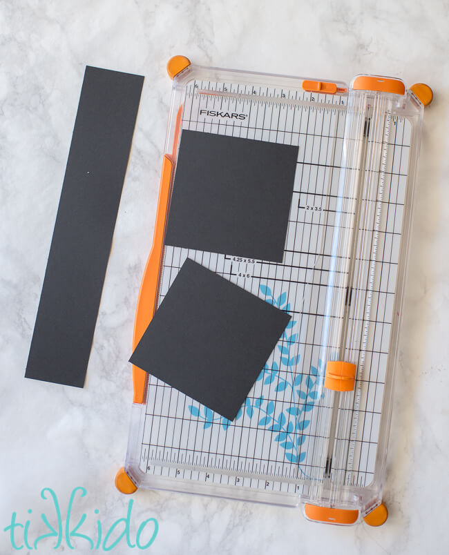 Black cardstock being cut into pieces to make Graduation Favors that look like graduation caps.