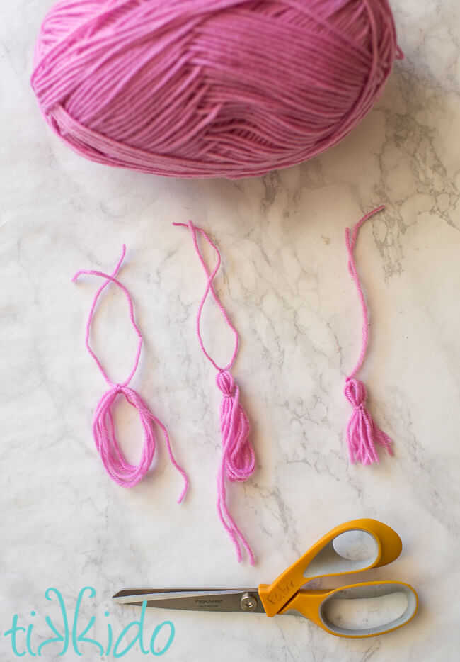 Pink yarn being formed into small tassels for Graduation Favors
