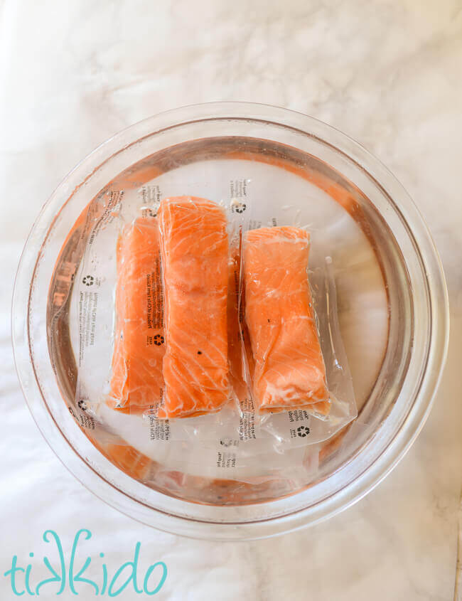 Frozen salmon defrosting in a bowl of warm water