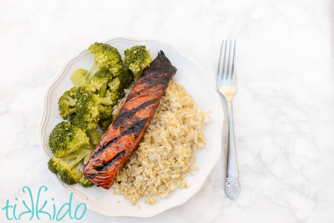 Grilled salmon on a white plate with broccoli and rice and quinoa