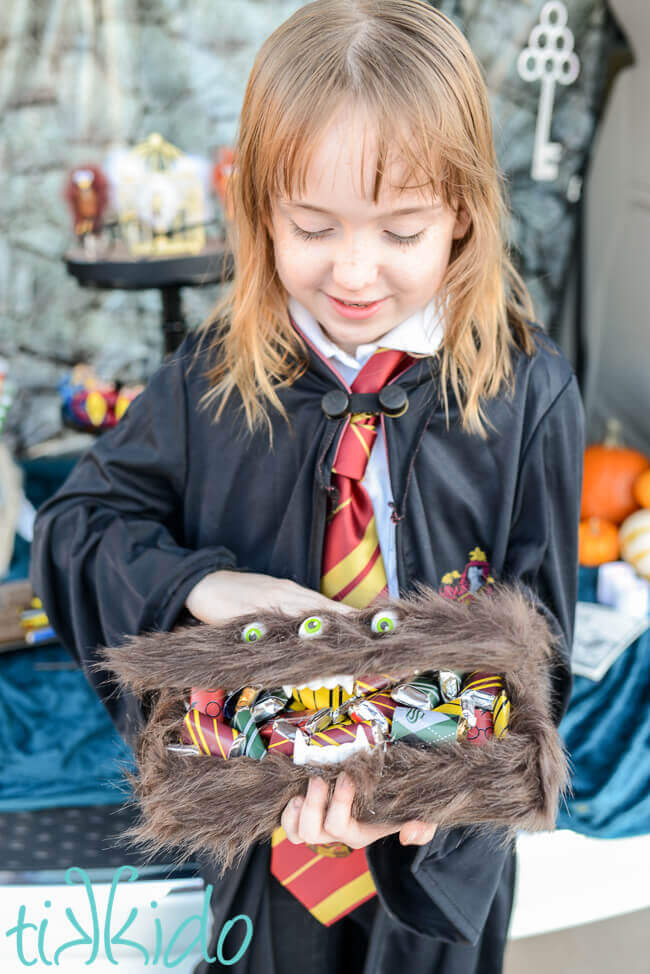 Harry Potter Monster book of Monsters box filled with Harry Potter candies, held by a girl dressed in Hogwarts Robes