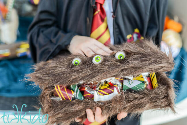 Harry Potter Monster book of Monsters box filled with Harry Potter candies, in the hands of a girl wearing Hogwarts robes.