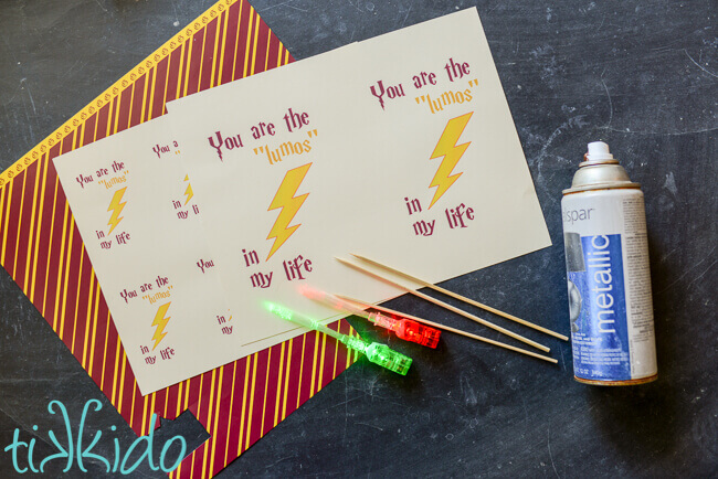 Harry Potter scrapbook paper, printed sheets of valentines, LED fiber optic finger lights, spray paint, and bamboo skewers on a black chalkboard background.