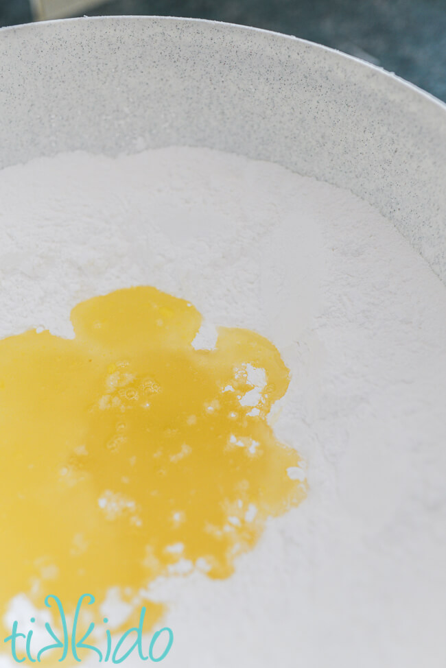 Liquid gelatin mixture in a bowl of powdered sugar for making homemade fondant.