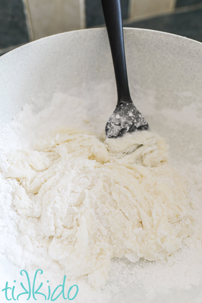 Homemade fondant being mixed in a large bowl with a black spatula.