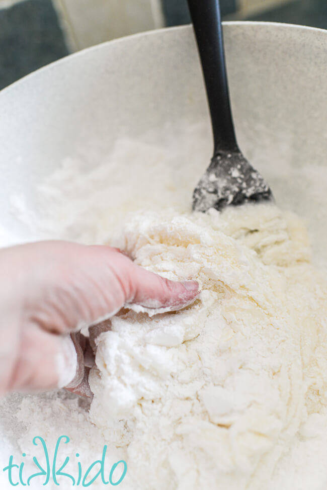 Hand mixing ingredients for homemade fondant in a large bowl.