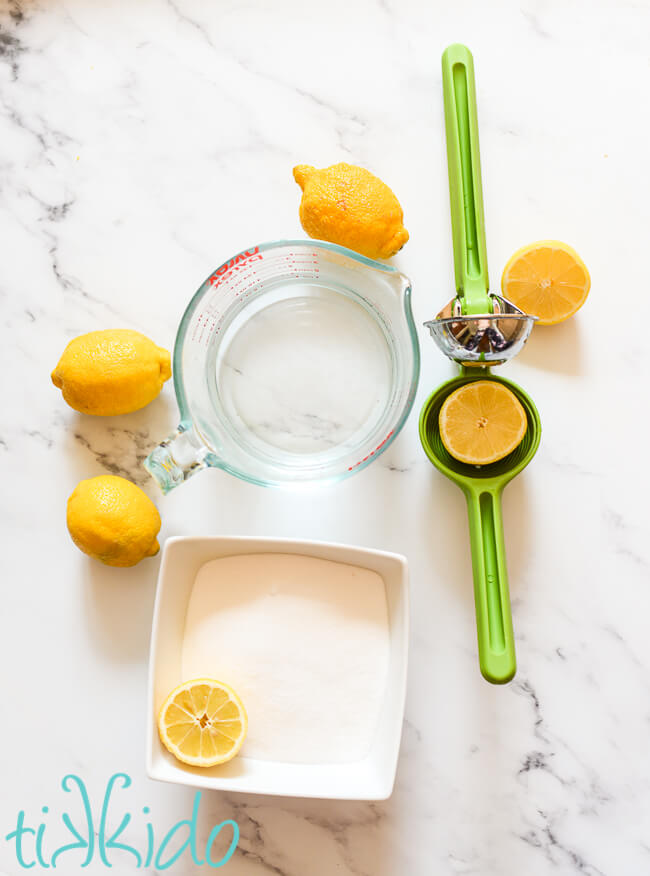 Ingredients for fresh lemonade on a white marble surface.