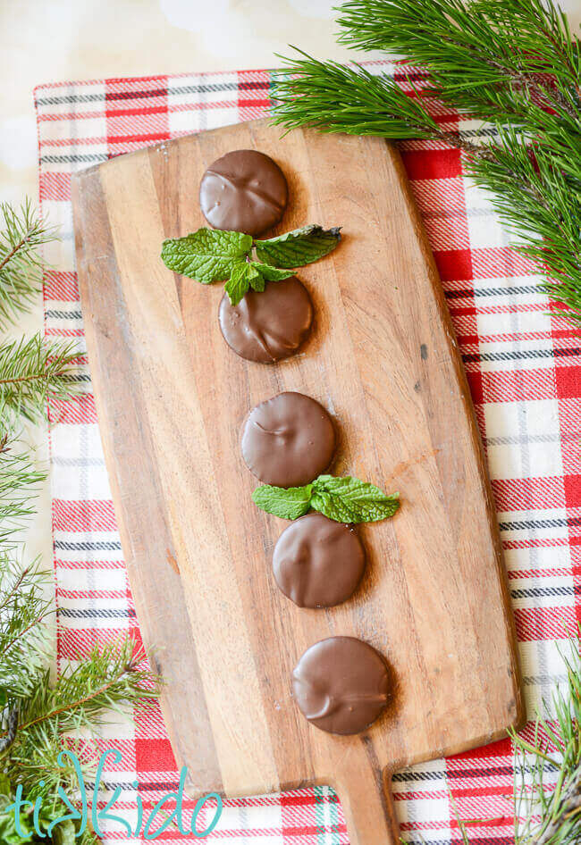 Homemade thin mints on a wooden cutting board.