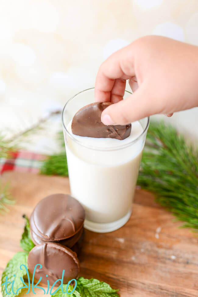 Homemade Thin Mint cookie being dunked in a tall glass of milk.