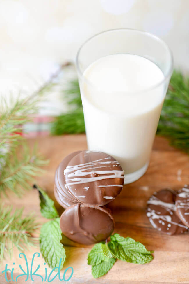 Stack of homemade thin mints cookies next to a tall glass of milk.