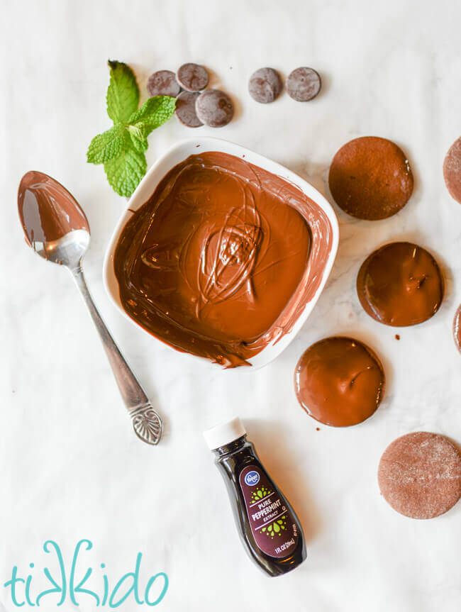 Homemade thin mints being dipped in melted mint chocolate.