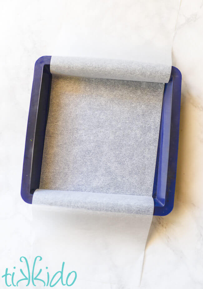 Blue silicone baking pan lined with parchment paper.