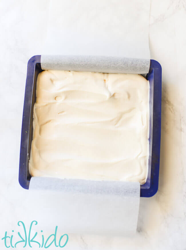 Silicone baking pan lined with parchment paper and filled with softened vanilla ice cream.