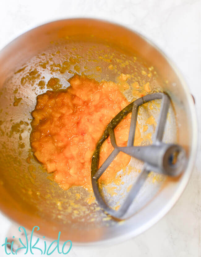 Fresh peaches for no churn peach ice cream being crushed using a Kitchenaid mixer.